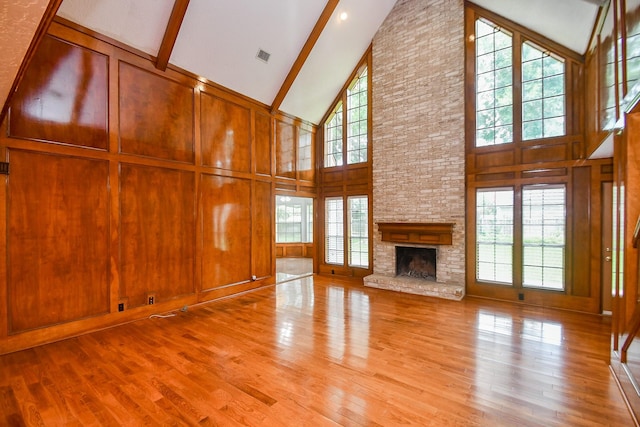 2622 Williams Grant St, Sugar Land, TX 77479 - unfurnished living room with high vaulted ceiling, beam ceiling, wood finished floors, a fireplace, and wood walls