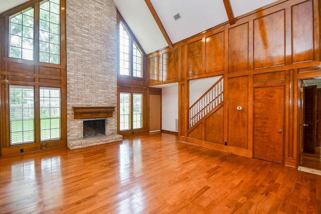 2622 Williams Grant St, Sugar Land, TX 77479 - unfurnished living room featuring high vaulted ceiling, beam ceiling, a fireplace, light wood-style floors, and stairway