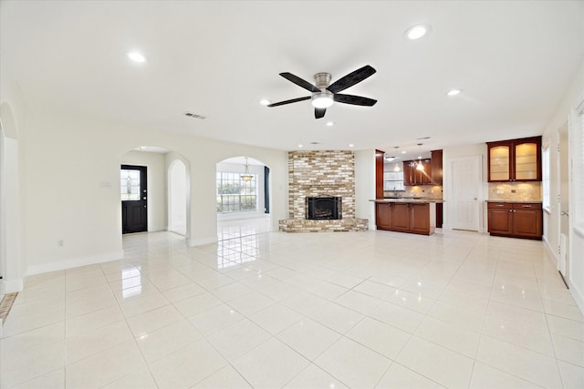 4530 T C Jester Blvd, Houston, TX 77018 - unfurnished living room featuring ceiling fan, recessed lighting, light tile patterned flooring, a brick fireplace, and arched walkways
