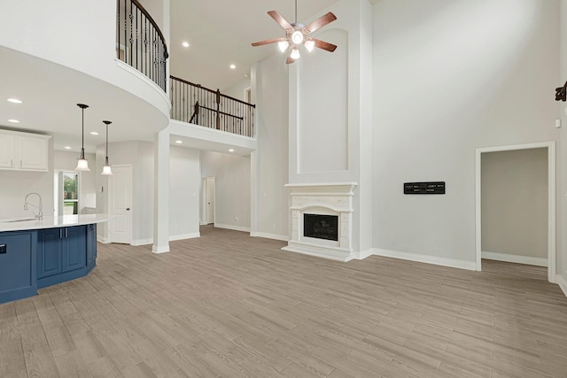 20010 Barrow Edge Ln, Cypress, TX 77433 - unfurnished living room featuring a towering ceiling, a ceiling fan, light wood finished floors, recessed lighting, and a fireplace with raised hearth