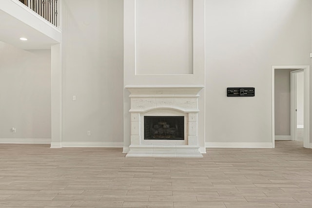 20010 Barrow Edge Ln, Cypress, TX 77433 - unfurnished living room with light wood-type flooring, a fireplace with raised hearth, and a high ceiling