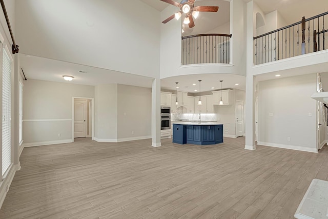 20010 Barrow Edge Ln, Cypress, TX 77433 - unfurnished living room with a ceiling fan, light wood-style flooring, and a towering ceiling