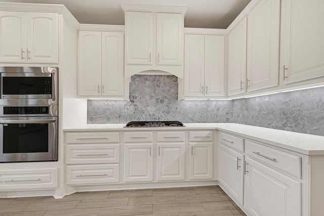 20010 Barrow Edge Ln, Cypress, TX 77433 - kitchen with appliances with stainless steel finishes, light countertops, backsplash, white cabinets, and wood finish floors