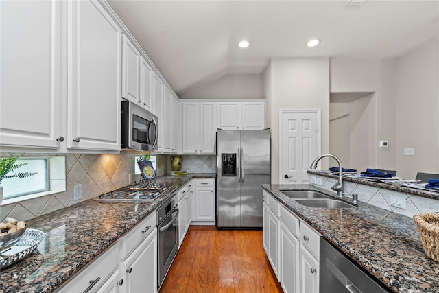 99 E Foxbriar Forest Cir, The Woodlands, TX 77382 - kitchen with stainless steel appliances, white cabinetry, wood finished floors, backsplash, and lofted ceiling