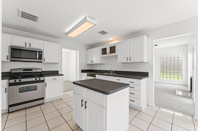 16323 Tiburon Way, Houston, TX 77053 - kitchen featuring stainless steel appliances, dark countertops, light tile patterned floors, white cabinets, and glass insert cabinets