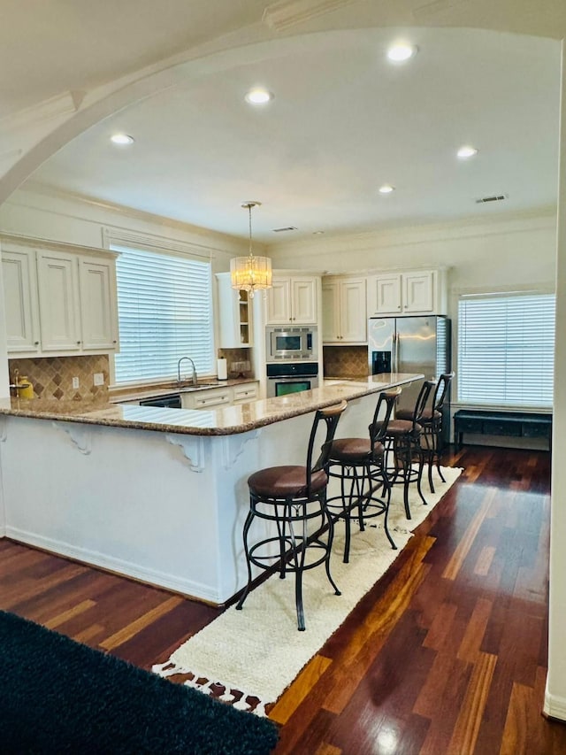 1812 Prospect St, Houston, TX 77004 - kitchen featuring stainless steel appliances, light stone countertops, a kitchen breakfast bar, plenty of natural light, and crown molding