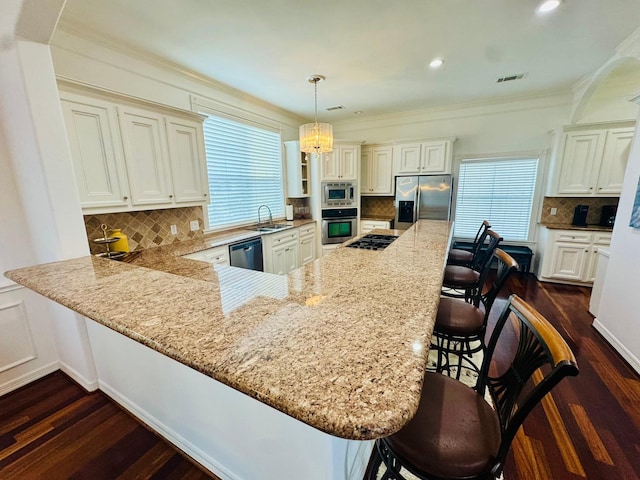 1812 Prospect St, Houston, TX 77004 - kitchen with stainless steel appliances, decorative backsplash, a kitchen bar, dark wood finished floors, and crown molding
