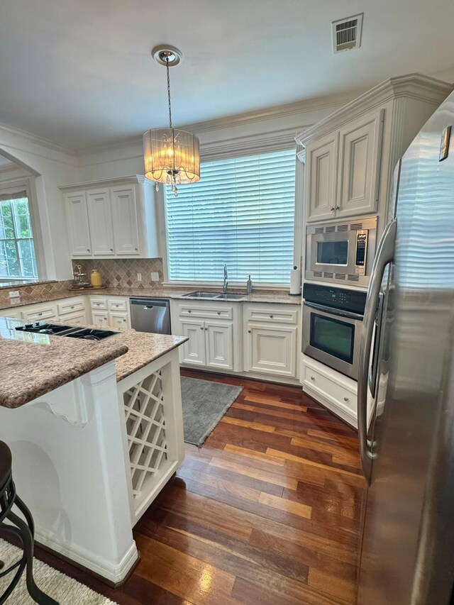 1812 Prospect St, Houston, TX 77004 - kitchen with appliances with stainless steel finishes, a chandelier, dark wood-style floors, white cabinets, and light stone countertops