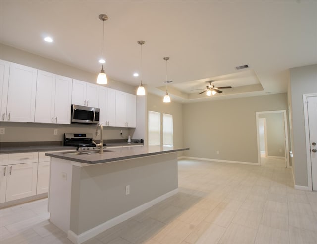324 Gans St Unit B, Houston, TX 77029 - kitchen with stainless steel appliances, a tray ceiling, dark countertops, ceiling fan, and a kitchen island with sink