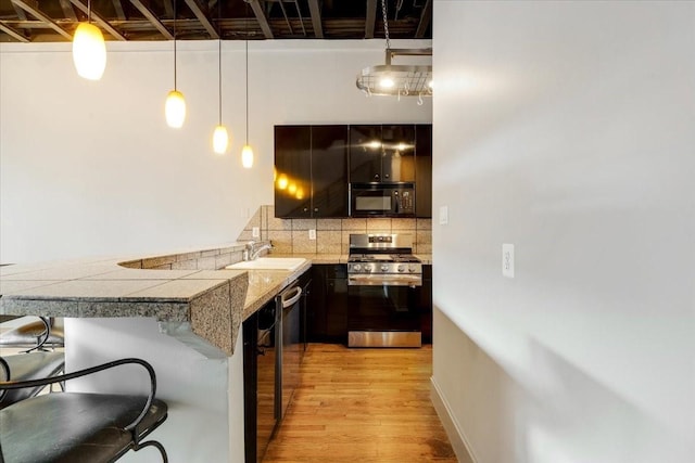 1020 Columbus St, Houston, TX 77019 - kitchen with stainless steel appliances, a breakfast bar, light wood-type flooring, decorative backsplash, and tile countertops