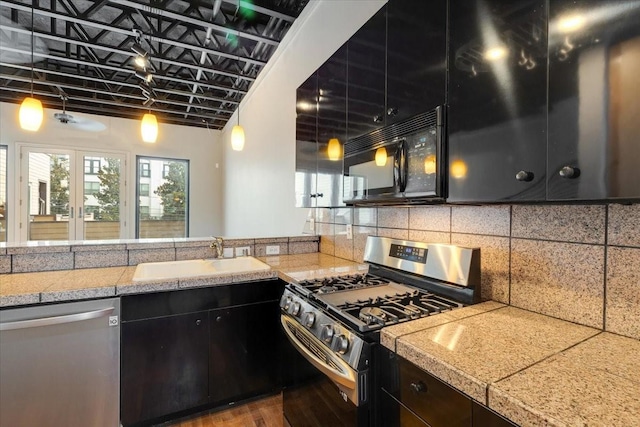 1020 Columbus St, Houston, TX 77019 - kitchen with stainless steel appliances, tile counters, backsplash, dark cabinetry, and wood finished floors