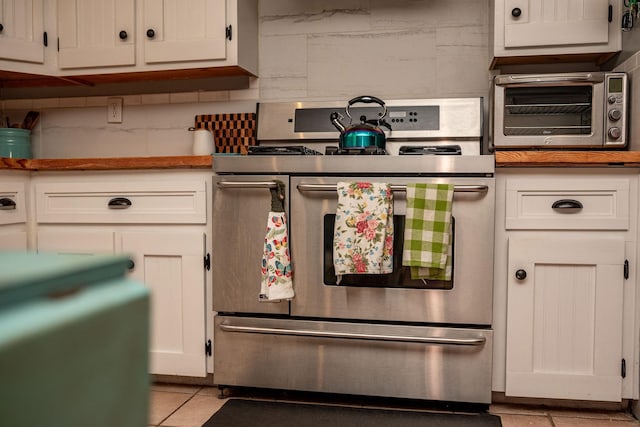 925 Royal Rd, Port Lavaca, TX 77979 - kitchen with electric range, tasteful backsplash, light tile patterned floors, and white cabinetry