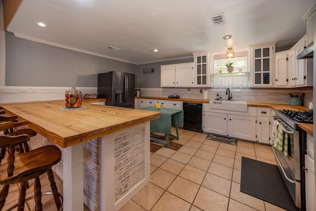 925 Royal Rd, Port Lavaca, TX 77979 - kitchen with black appliances, wood counters, crown molding, light tile patterned floors, and a kitchen bar