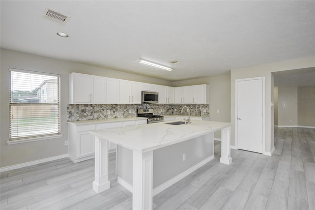 7255 Liberty Mesa Ln, Houston, TX 77049 - kitchen featuring stainless steel appliances, backsplash, light wood-style flooring, and white cabinetry