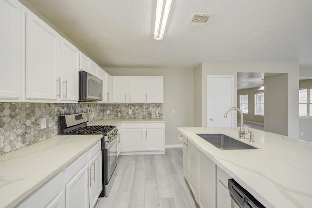 7255 Liberty Mesa Ln, Houston, TX 77049 - kitchen featuring stainless steel appliances, light wood-type flooring, backsplash, white cabinetry, and light stone counters