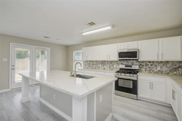 7255 Liberty Mesa Ln, Houston, TX 77049 - kitchen with stainless steel gas range, backsplash, light stone counters, white cabinets, and light wood-type flooring