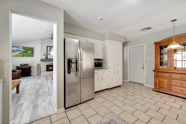 15707 Spring Forest Dr, Houston, TX 77059 - kitchen featuring appliances with stainless steel finishes, white cabinetry, a fireplace, hanging light fixtures, and vaulted ceiling