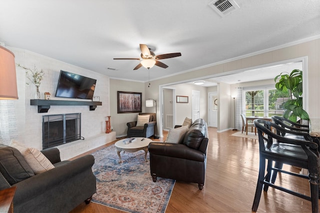 32047 S Wiggins St, Magnolia, TX 77355 - living room featuring wood finished floors, a ceiling fan, a brick fireplace, and crown molding