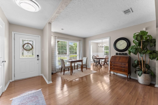 32047 S Wiggins St, Magnolia, TX 77355 - foyer with a chandelier, a textured ceiling, and light wood-type flooring