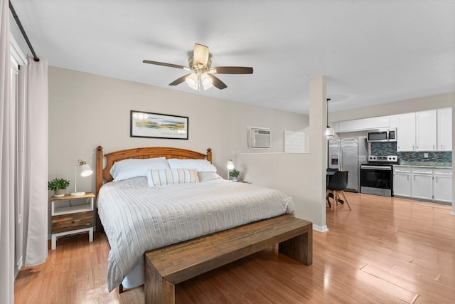 32047 S Wiggins St, Magnolia, TX 77355 - bedroom featuring stainless steel fridge, light wood-type flooring, a wall unit AC, and ceiling fan