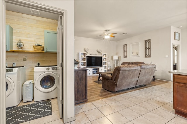 18715 Deer Trace Dr, Crosby, TX 77532 - laundry room featuring washing machine and dryer, a ceiling fan, light tile patterned floors, cabinet space, and wooden walls