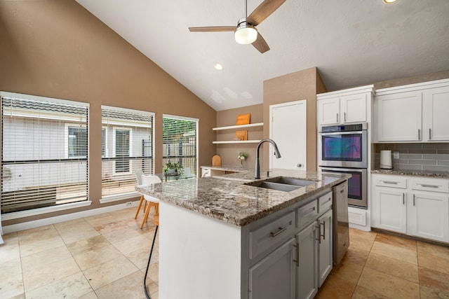 6115 Downwood Forest Dr, Houston, TX 77088 - kitchen featuring stainless steel double oven, ceiling fan, open shelves, decorative backsplash, and light stone counters