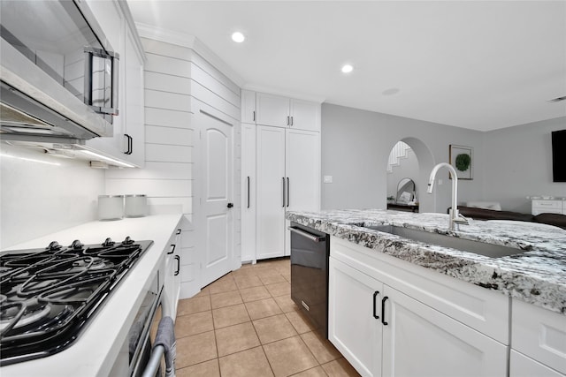14314 Prosper Ridge Dr, Cypress, TX 77429 - kitchen featuring stainless steel microwave, black gas cooktop, light tile patterned floors, arched walkways, and white cabinets
