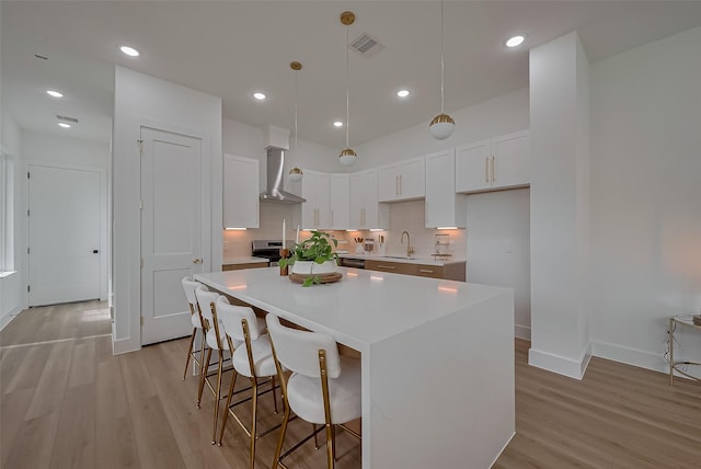 776 Mansfield St, Houston, TX 77091 - kitchen with wall chimney exhaust hood, light wood-type flooring, a center island, tasteful backsplash, and white cabinets