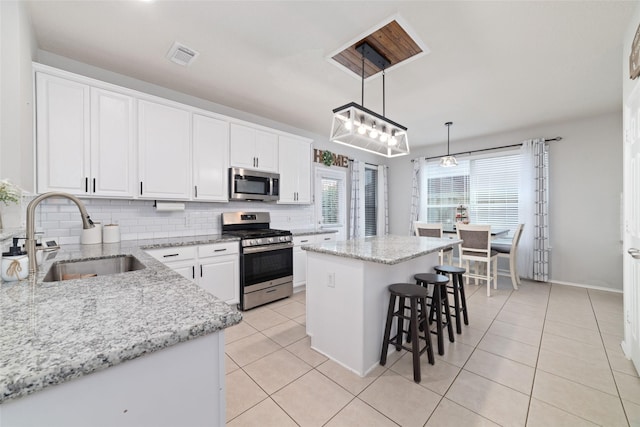 18914 Woodglen Shadows Dr, Humble, TX 77346 - kitchen featuring stainless steel appliances, a kitchen island, tasteful backsplash, white cabinetry, and light tile patterned floors