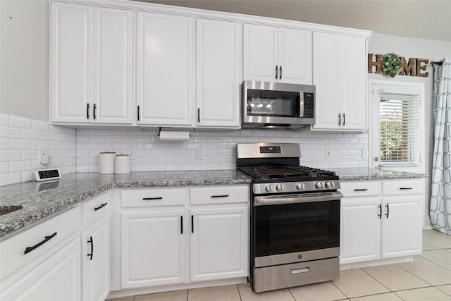 18914 Woodglen Shadows Dr, Humble, TX 77346 - kitchen featuring appliances with stainless steel finishes, backsplash, white cabinetry, and light stone countertops