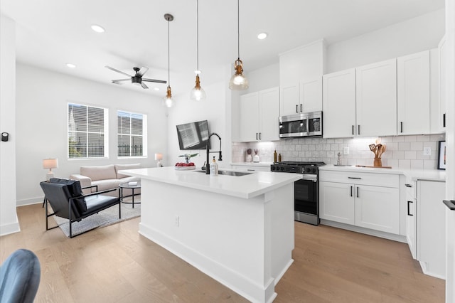 2213 Springwood Vista Ln, Houston, TX 77055 - kitchen featuring stainless steel appliances, open floor plan, tasteful backsplash, light wood finished floors, and a ceiling fan
