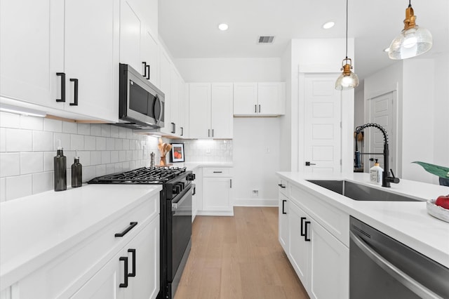 2213 Springwood Vista Ln, Houston, TX 77055 - kitchen with stainless steel appliances, light wood-type flooring, hanging light fixtures, white cabinetry, and backsplash