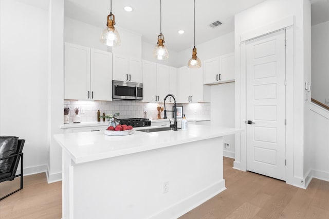 2213 Springwood Vista Ln, Houston, TX 77055 - kitchen featuring stainless steel microwave, light wood finished floors, white cabinets, tasteful backsplash, and light countertops