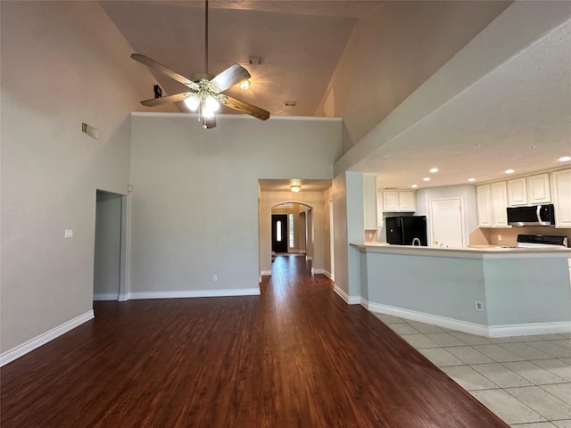 12807 Stratford Heights Dr, Sugar Land, TX 77498 - unfurnished living room featuring a high ceiling, arched walkways, ceiling fan, and light wood-type flooring