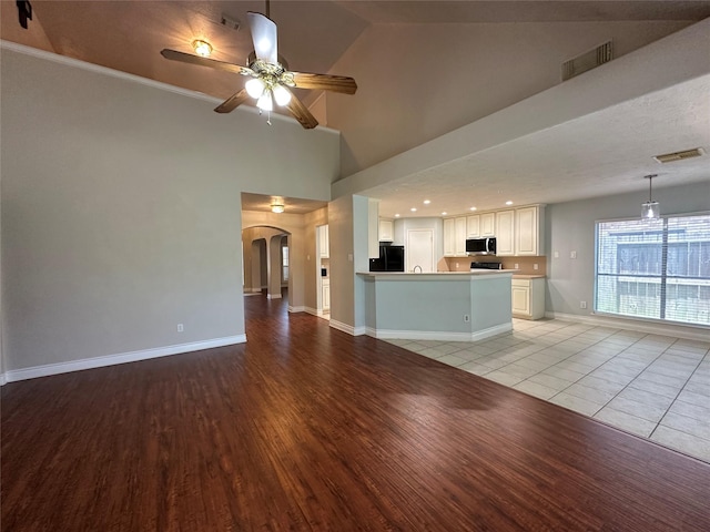 12807 Stratford Heights Dr, Sugar Land, TX 77498 - unfurnished living room featuring arched walkways, light wood-type flooring, ceiling fan, and a high ceiling
