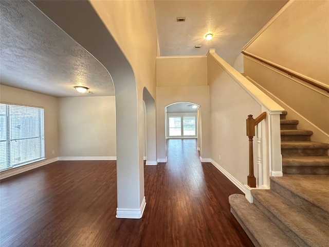12807 Stratford Heights Dr, Sugar Land, TX 77498 - unfurnished living room with arched walkways, wood finished floors, a textured ceiling, and stairs