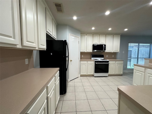 12807 Stratford Heights Dr, Sugar Land, TX 77498 - kitchen with stainless steel microwave, white gas range oven, freestanding refrigerator, light tile patterned floors, and white cabinetry