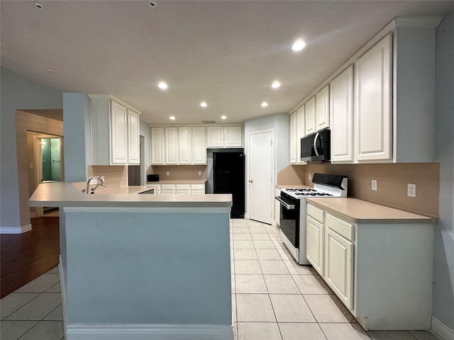 12807 Stratford Heights Dr, Sugar Land, TX 77498 - kitchen featuring black appliances, a peninsula, light tile patterned floors, recessed lighting, and light countertops