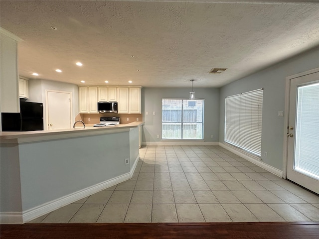 12807 Stratford Heights Dr, Sugar Land, TX 77498 - kitchen with fridge, stainless steel microwave, stove, light tile patterned floors, and white cabinets