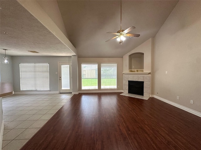 12807 Stratford Heights Dr, Sugar Land, TX 77498 - unfurnished living room with plenty of natural light, ceiling fan, a tile fireplace, vaulted ceiling, and wood finished floors