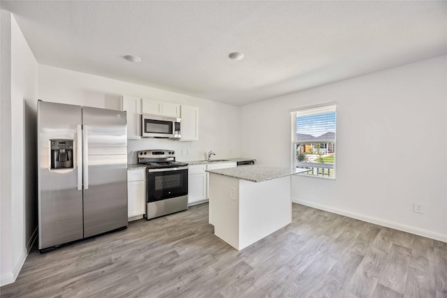 16515 Jasmine Marie Pl, Conroe, TX 77306 - kitchen with appliances with stainless steel finishes, light wood-style floors, white cabinets, and light stone counters