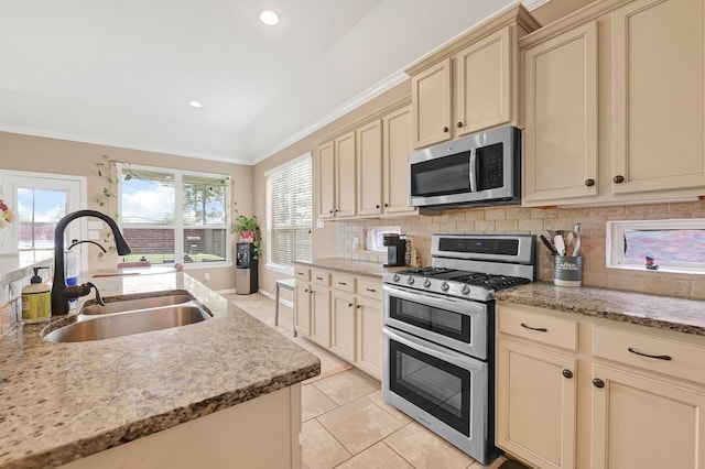 19443 Alton Springs Dr, Cypress, TX 77433 - kitchen featuring stainless steel appliances, cream cabinetry, tasteful backsplash, light tile patterned flooring, and light stone countertops