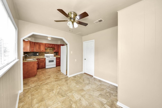 9417 Fairland Dr, Houston, TX 77051 - kitchen with white appliances, a ceiling fan, under cabinet range hood, arched walkways, and tasteful backsplash