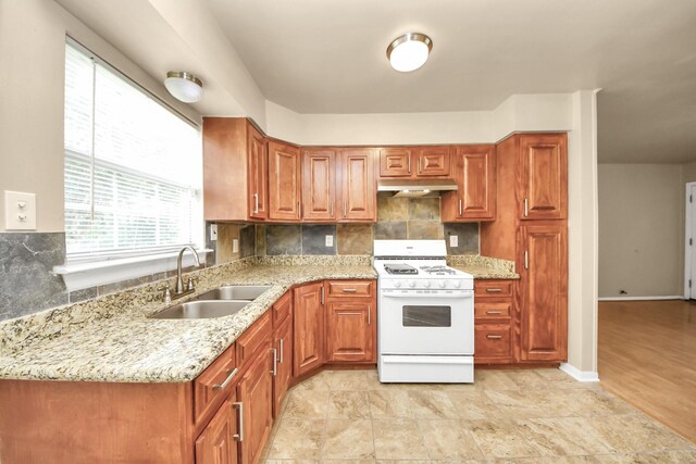9417 Fairland Dr, Houston, TX 77051 - kitchen with white gas range oven, under cabinet range hood, decorative backsplash, and light stone countertops