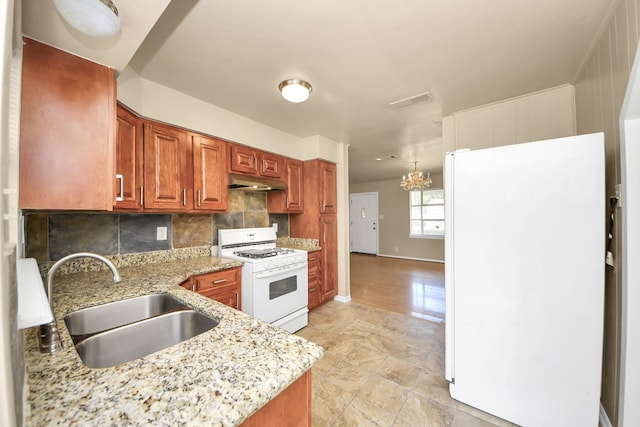 9417 Fairland Dr, Houston, TX 77051 - kitchen featuring white appliances, under cabinet range hood, decorative backsplash, a chandelier, and light stone counters