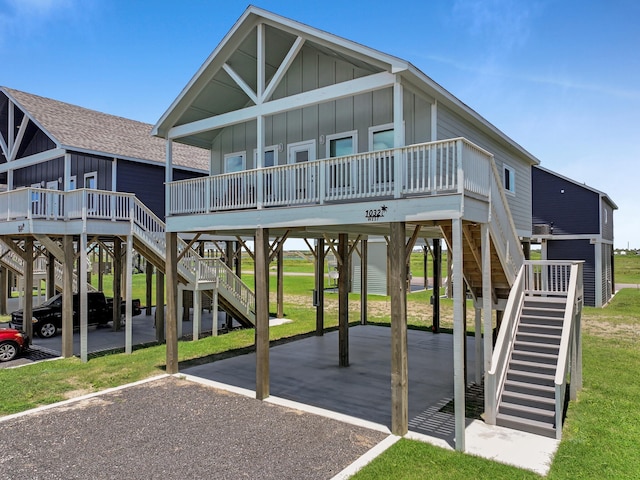 1032 Sunset Cir W, Crystal Beach, TX 77650 - view of front facade featuring stairway, a carport, board and batten siding, driveway, and covered porch