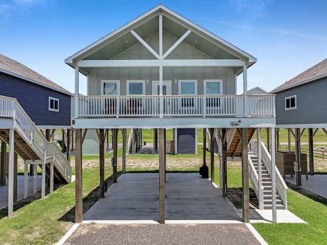 1032 Sunset Cir W, Crystal Beach, TX 77650 - view of front of house with stairway, board and batten siding, a porch, and a front lawn