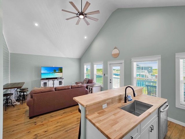 1032 Sunset Cir W, Crystal Beach, TX 77650 - kitchen featuring stainless steel dishwasher, light wood finished floors, high vaulted ceiling, ceiling fan, and white cabinets