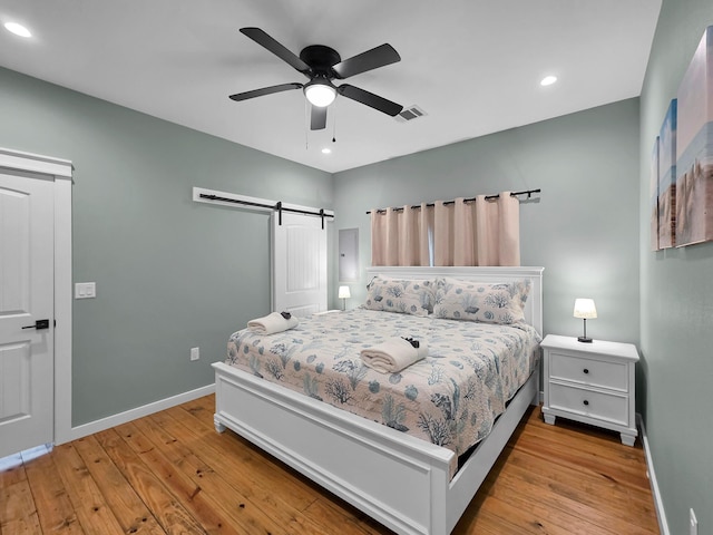 1032 Sunset Cir W, Crystal Beach, TX 77650 - bedroom with hardwood / wood-style flooring, recessed lighting, a barn door, and a ceiling fan