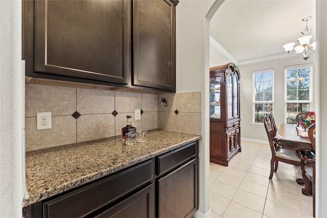 1115 Tydeman Ct, Katy, TX 77494 - kitchen with ornamental molding, tasteful backsplash, dark brown cabinets, arched walkways, and dark stone counters